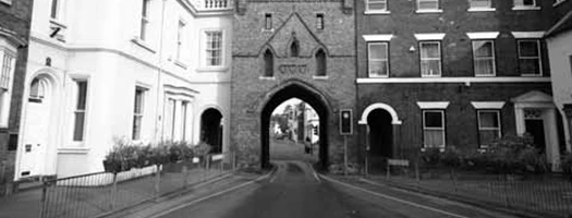 Black and white image of North Bar between brick buildings on a narrow street in Beverley
