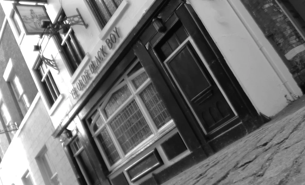 Exterior of Black Boy pub with traditional British pub and hanging sign, black and white architectural photo