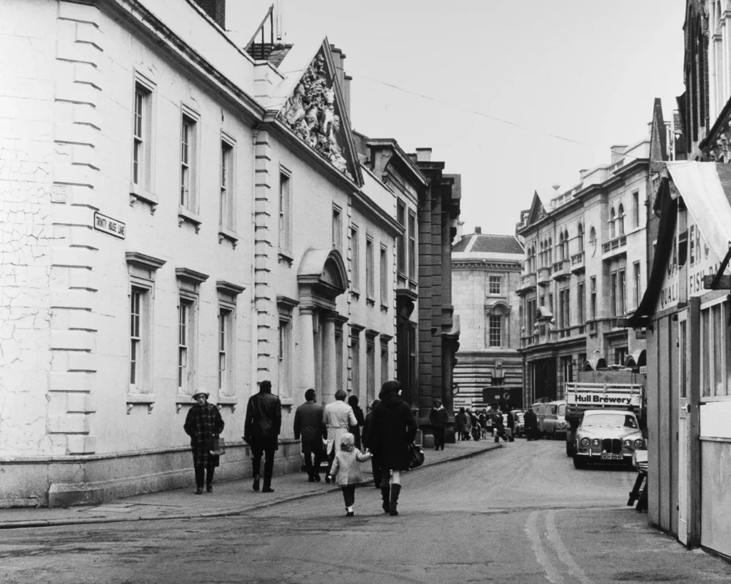 Black and white photo of Trinity House Lane with vintage buildings, pedestrians, and a Hull Brewery truck in UK